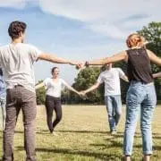 Group of young adults holding hands in a circle outside playing field