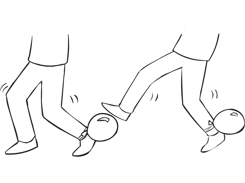 Person attempting to stand on the balloon tied to partner's ankle, in fun energiser called Balloon Tag game