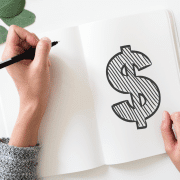 Person drawing dollar sign on notebook hoping for playmeo discount coupon