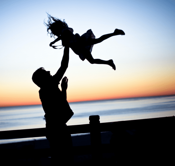 Man throwing child in air as part of team building trust activities they do together