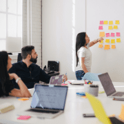 Woman pointing to sticky notes about 12 simple team building activities. Credit You X Ventures