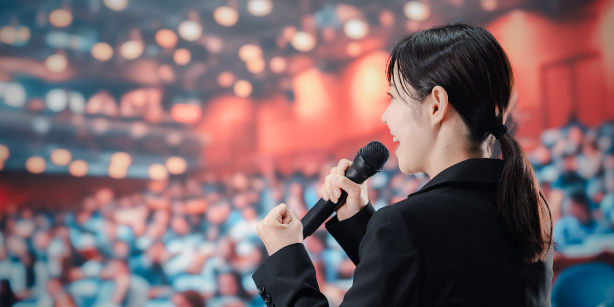 Woman speaking to large group wondering what to do with 150 people