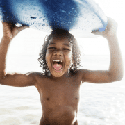 Boy carrying surfboard as one of the things your kids need to do
