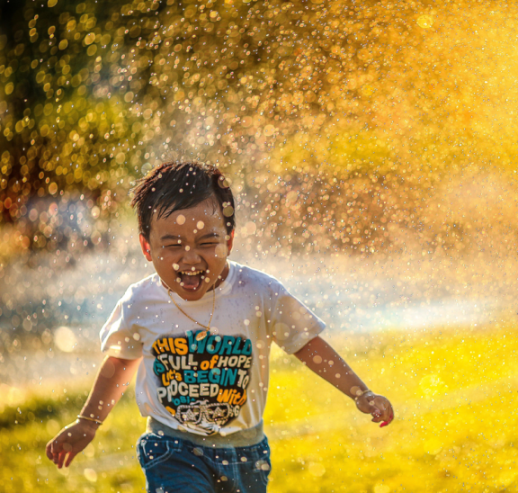 Boy running through sprinkler water game