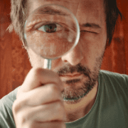 Man with a question looking through magnifying glass
