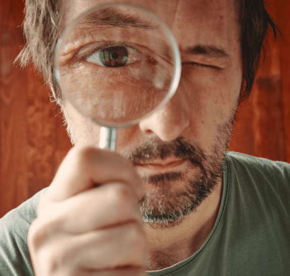 Man with a question looking through magnifying glass